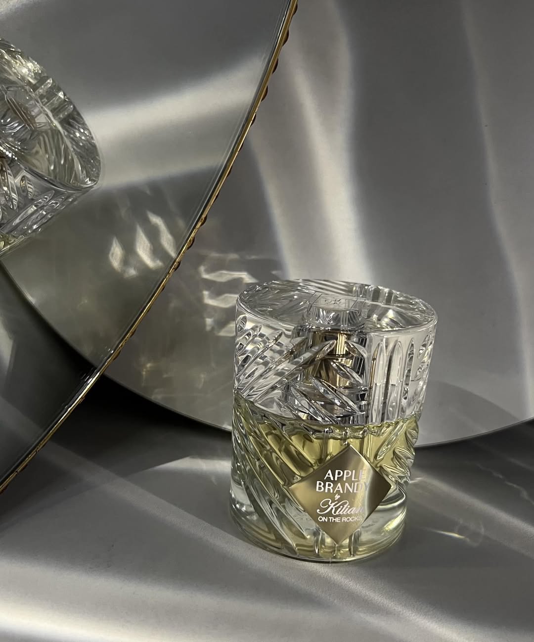 Chai Apple Brandy đứng cạnh ánh đèn vàng ấm, nền là một buổi tối bar sang trọng phong cách New York.